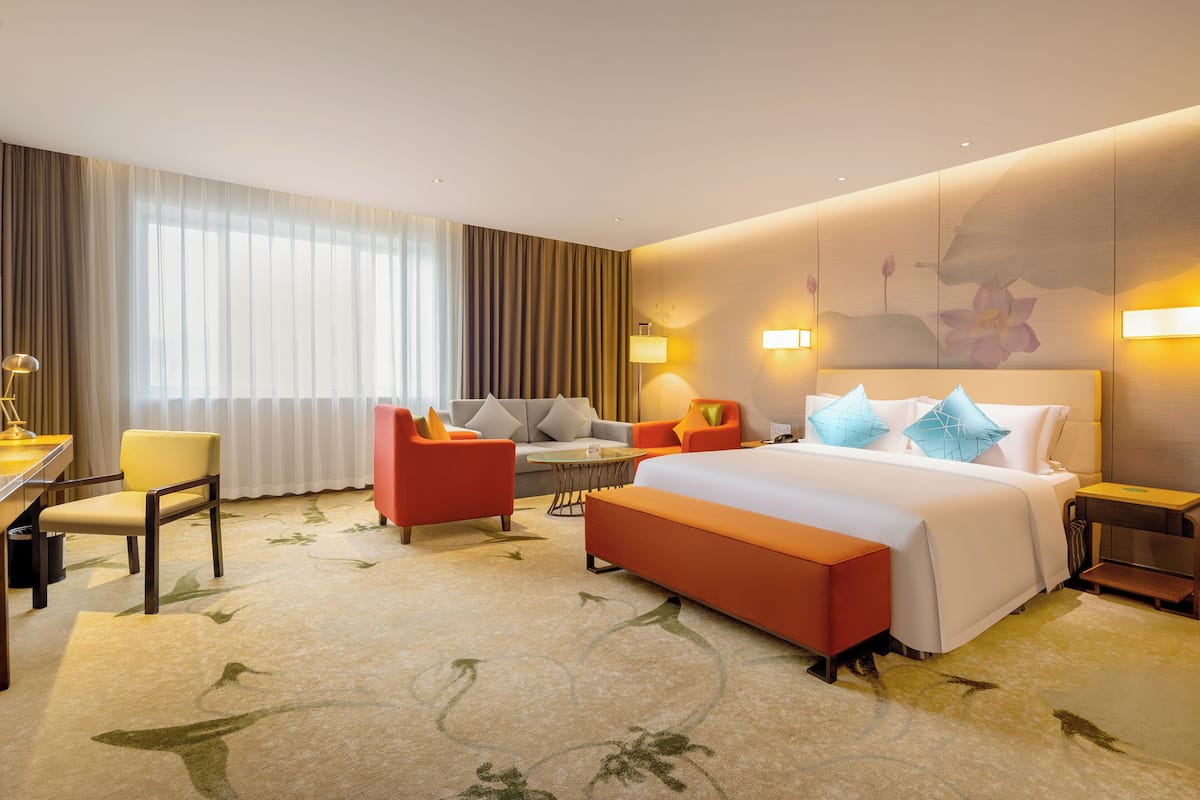 Een hotelkamer met een groot bed, een bureau, een stoel, een bank en een kleine tafel.
