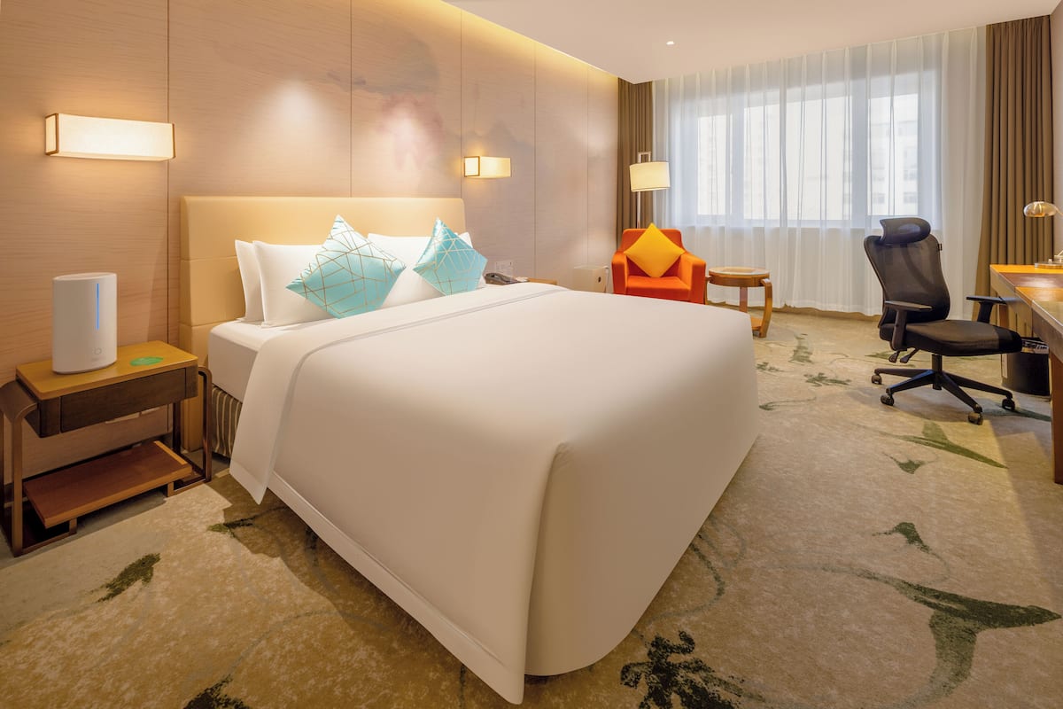 Een hotelkamer met een groot bed, een bureau, een stoel en een nachtkastje.