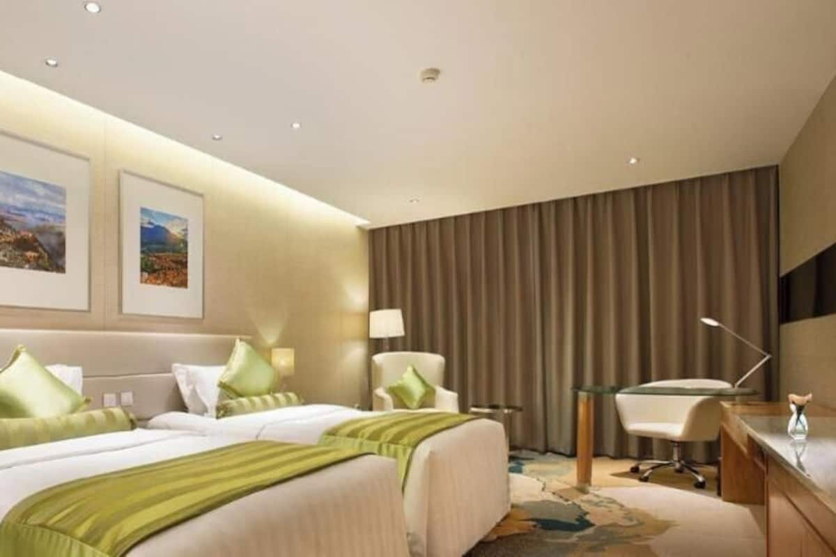 Een hotelkamer met een bed, twee ingelijste foto's aan de muur, een bureau en een stoel.
