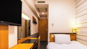 Una habitación de hotel con cama, escritorio, silla, televisor y espejo.