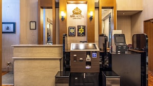 Un área de recepción con un mostrador de madera, un quiosco digital y una cafetera.