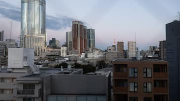 Paisagem urbana com edifícios altos modernos, incluindo um arranha-céu com design curvo e um edifício alto com uma torre vermelha.