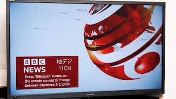 Uma televisão exibindo a BBC News 11CH com um design abstrato vermelho e branco.