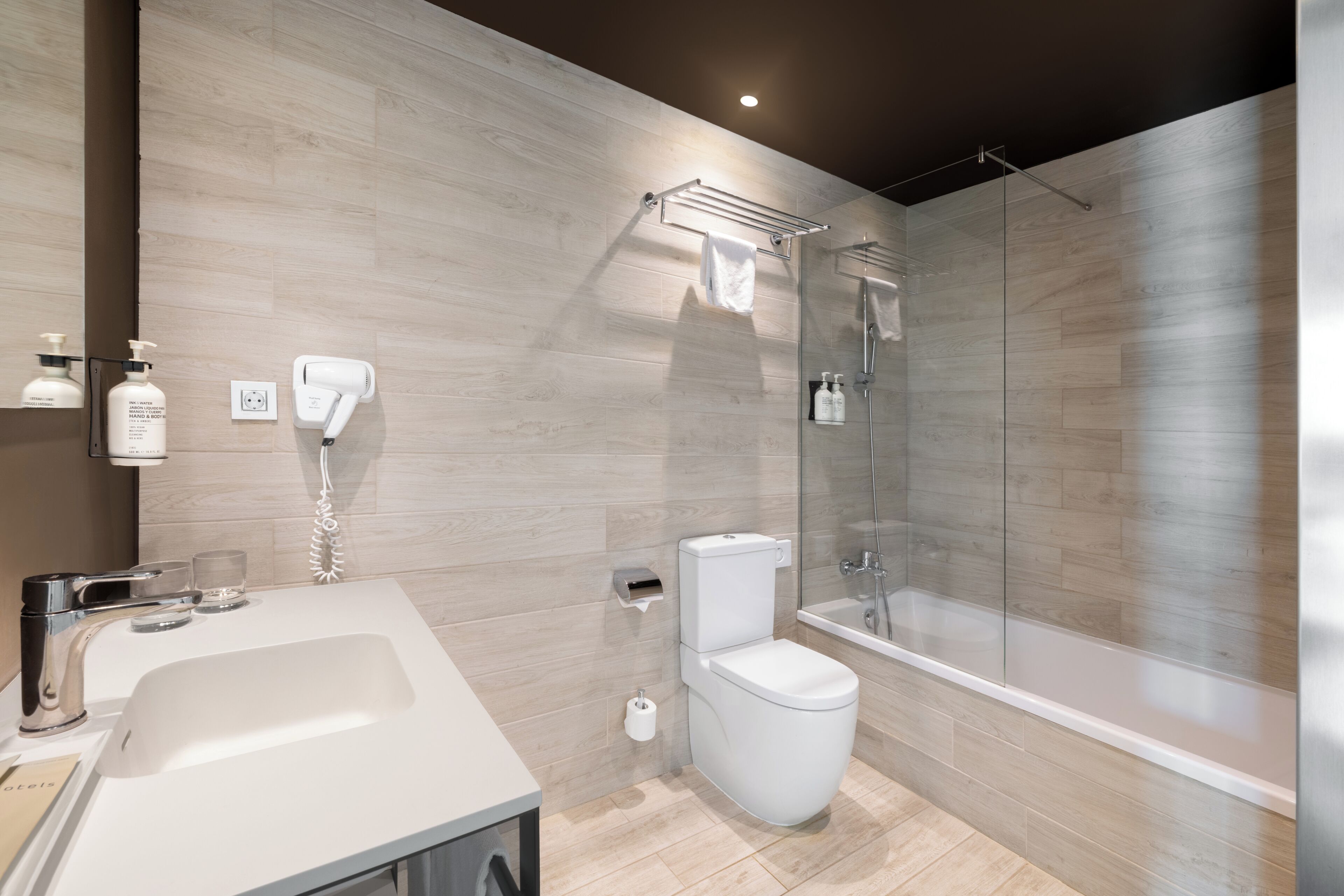 Un baño moderno con lavamanos grande, inodoro y ducha con mampara de vidrio.