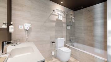 Un baño moderno con lavamanos grande, inodoro y ducha con mampara de vidrio.