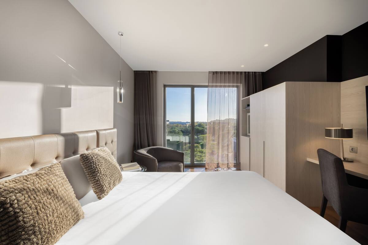 Quarto de hotel moderno com uma cama grande, uma escrivaninha e uma cadeira.