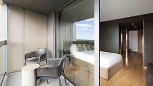 A modern bedroom with a large bed, a glass wall, and a balcony with seating. - Hotel SB BCN Events 4 Sup (Castelldefels)