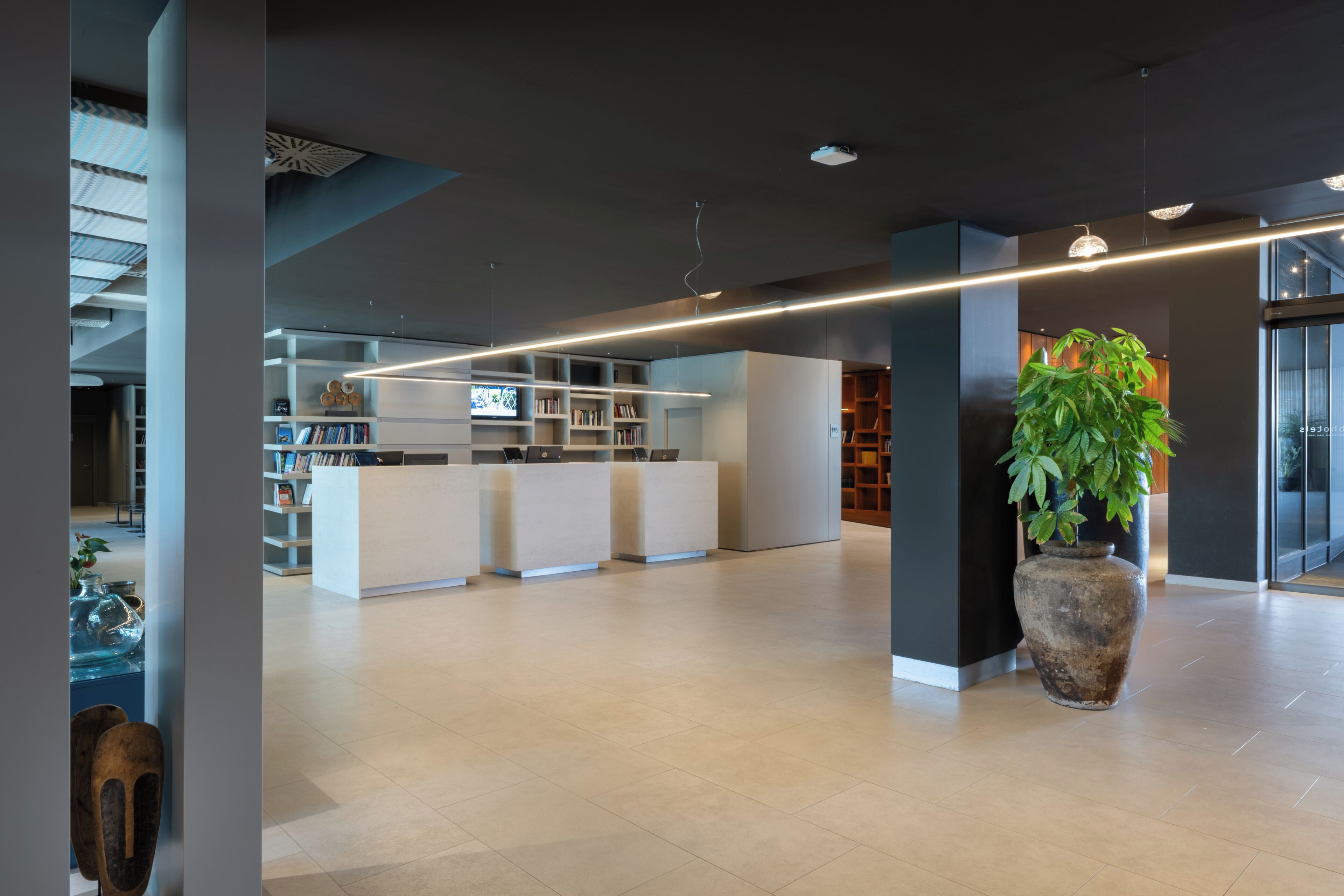 Een moderne receptie met een receptiebalie, een zithoek en een grote kamerplant.