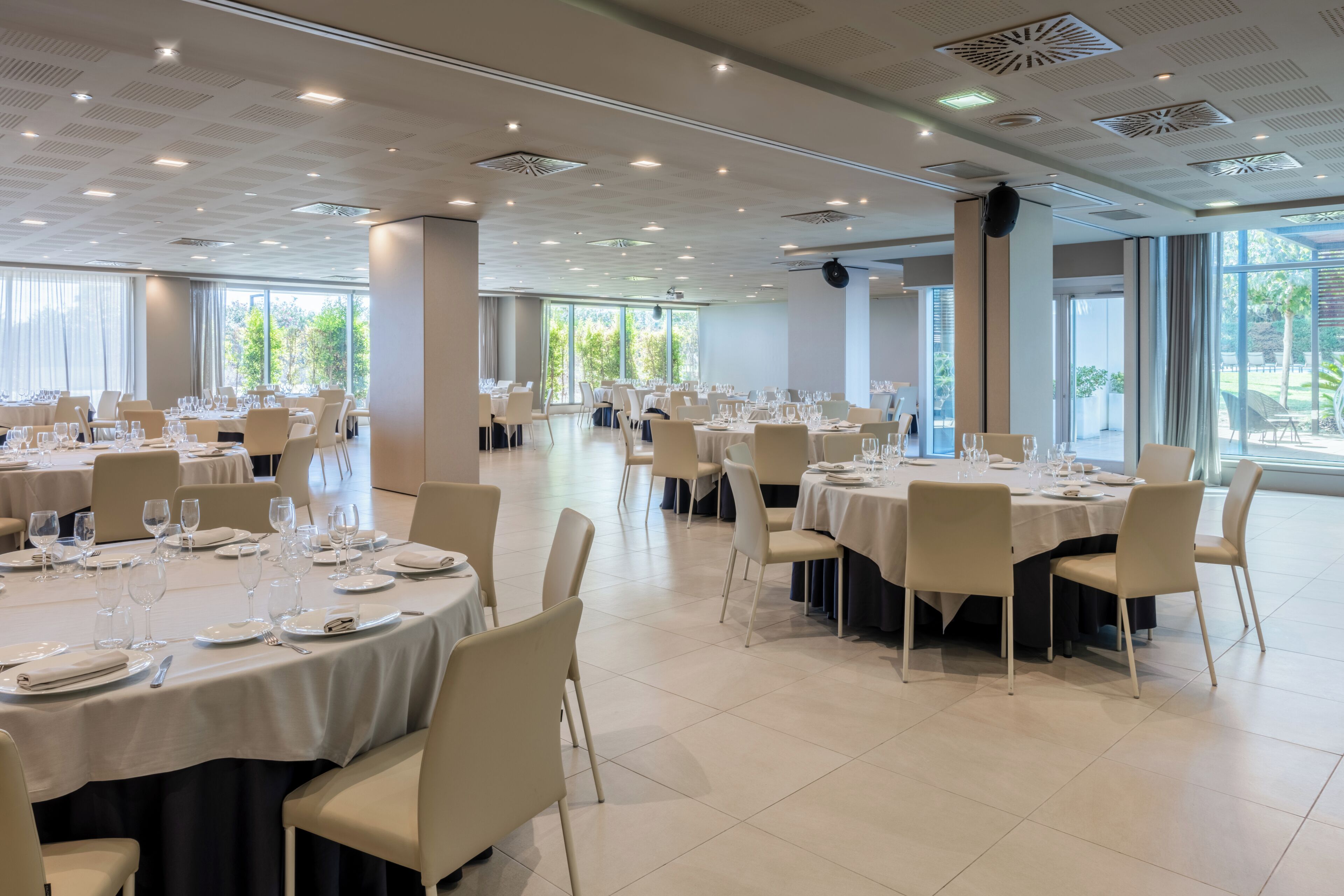 A spacious dining area with round tables, chairs, and neatly arranged table settings.