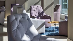 A modern interior with a sofa, armchairs, a small wooden table, and a bookshelf. - Hotel SB BCN Events 4 Sup (Castelldefels)