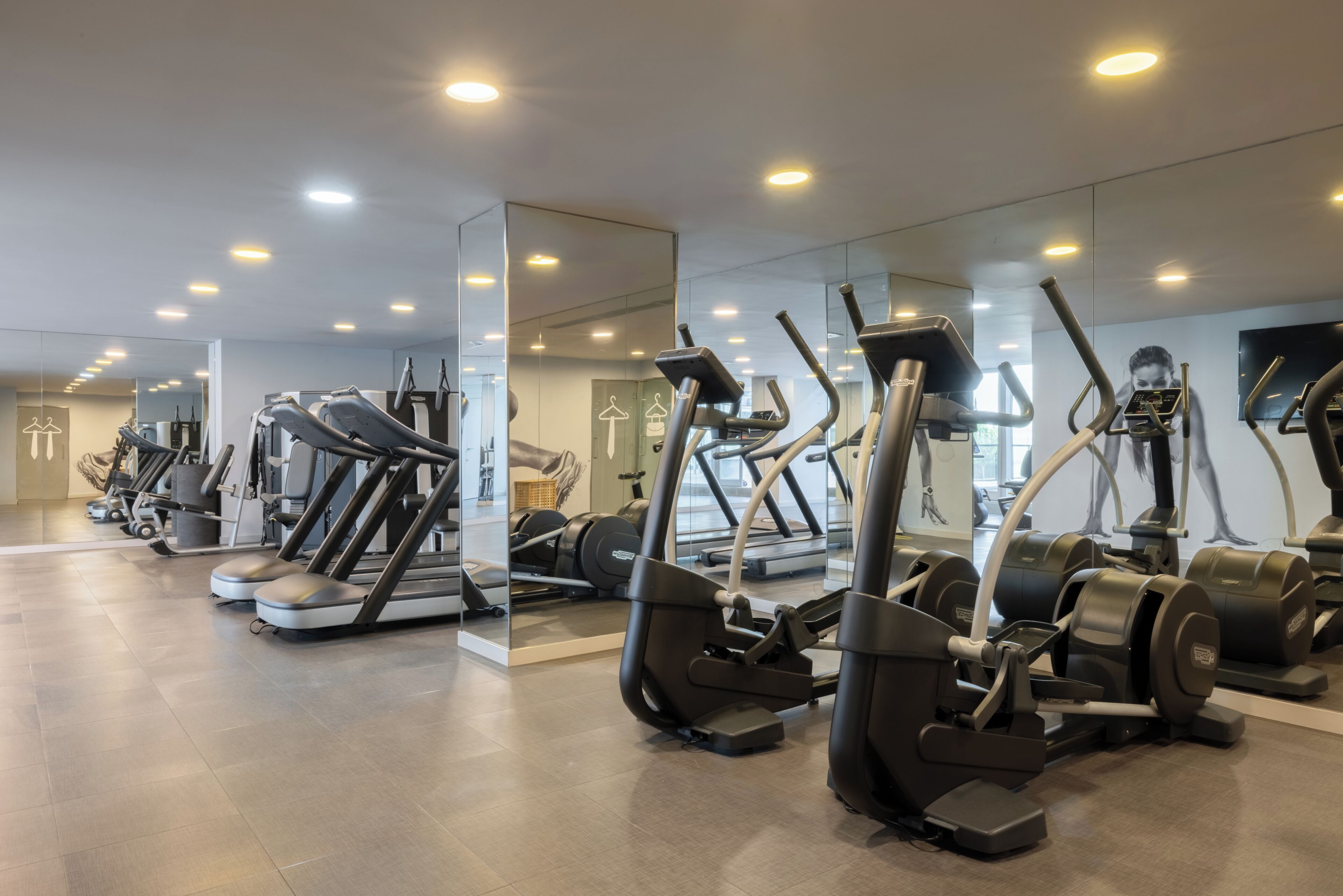 Un gimnasio con cintas de correr, elípticas y máquinas de pesas.