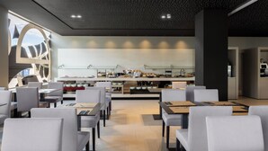A modern restaurant with a central counter, seating area with tables and chairs, and a ceiling with a starry design. - Hotel SB BCN Events 4 Sup (Castelldefels)