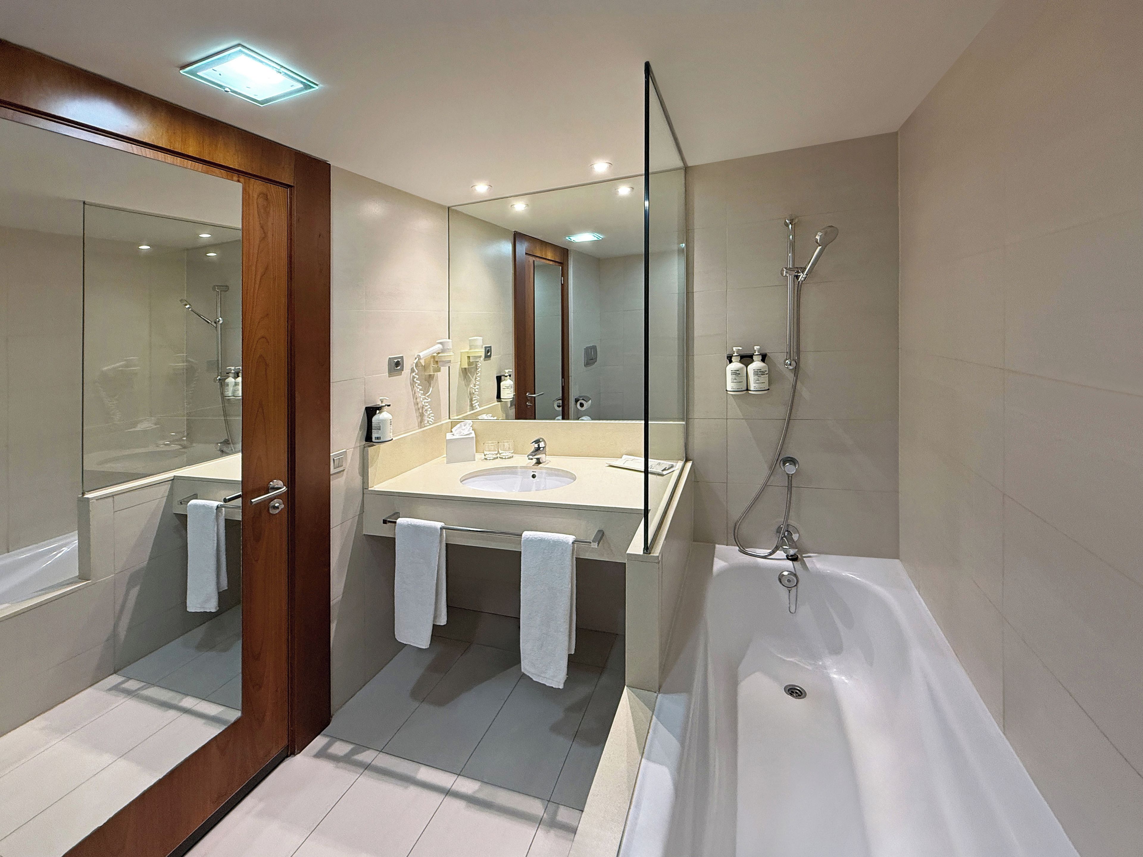 Un baño moderno con ducha de vidrio, bañera independiente y tocador con espejo.