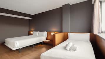 A hotel room with two beds, wooden headboards, a nightstand, and a window with curtains.