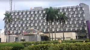 Un hotel de varios pisos con una fachada uniforme, que cuenta con balcones y una entrada central con una exhibición de banderas.