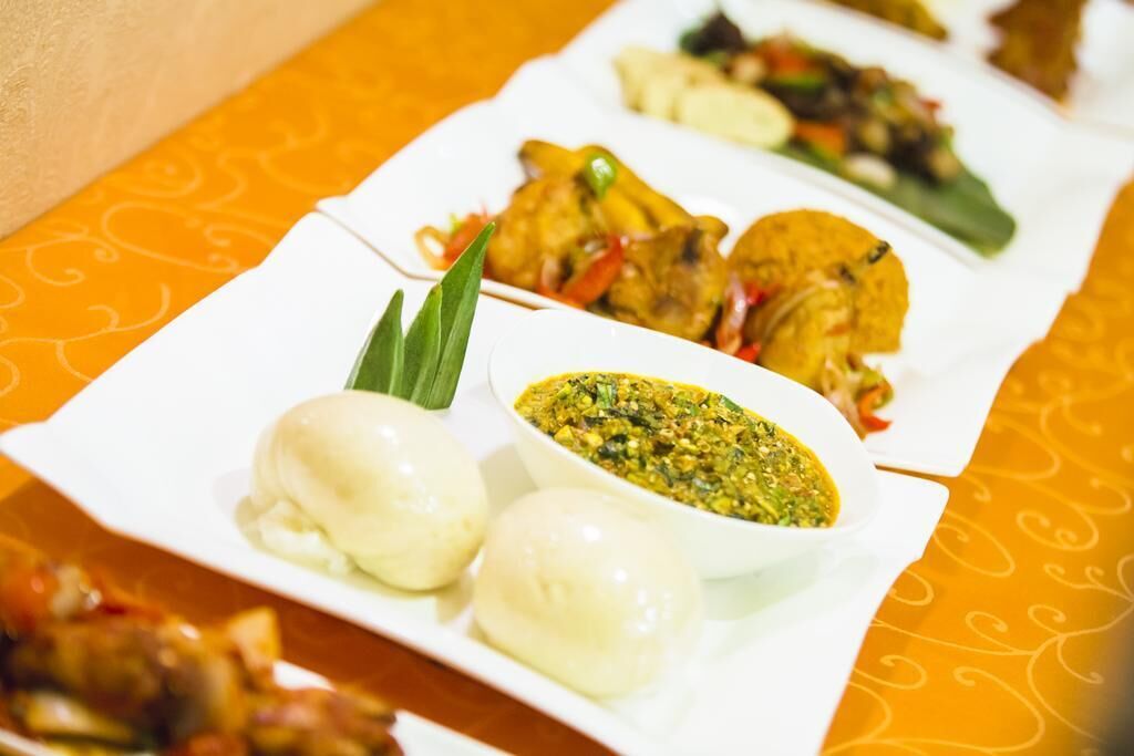 Una mesa con varios platos, entre ellos dumplings, una salsa verde y carne a la parrilla.
