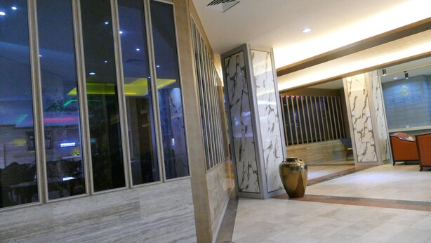 Un vestíbulo de hotel moderno con suelo de mármol, ventanas amplias y una recepción.