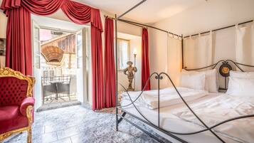 A room with a bed, a red chair, and a balcony with red curtains.
