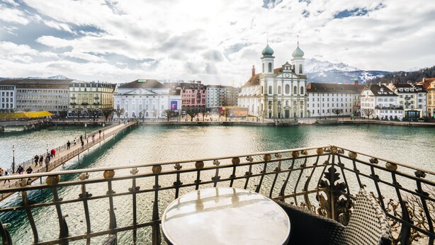 A riverside view with a bridge, historic buildings, and a mountain backdrop. - Altstadt Hotel Magic Luzern (Lucerne)