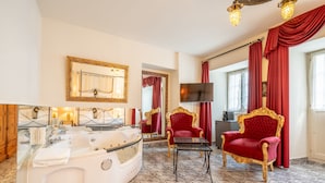 A luxurious bathroom with a large bathtub, two red velvet armchairs, a gold-framed mirror, and a flat-screen TV. - Altstadt Hotel Magic Luzern (Lucerne)