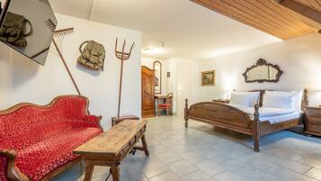 Una habitación con una cama de madera, un sofá rojo, una mesa de madera, un espejo y un techo de madera.