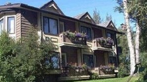 A two-story house with a balcony on the second floor, surrounded by greenery. - Soldotna Alaska Fishing Lodge (Soldotna)