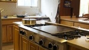 A kitchen with wooden cabinets, a large stove, and a window. - Soldotna Alaska Fishing Lodge (Soldotna)