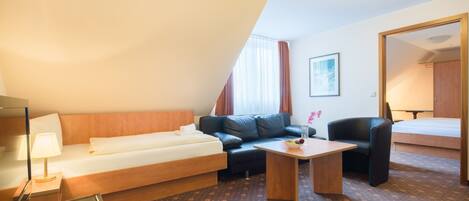 Una habitación de hotel con cama, sofá, escritorio y una silla.