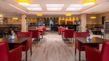 Un restaurante moderno con sillas y mesas rojas, una zona de bar y suelo de madera.
