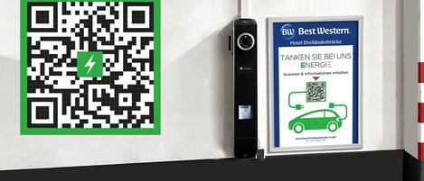 A QR code and a sign for Best Western Hotel Dreiländerbrücke with a car charging station.