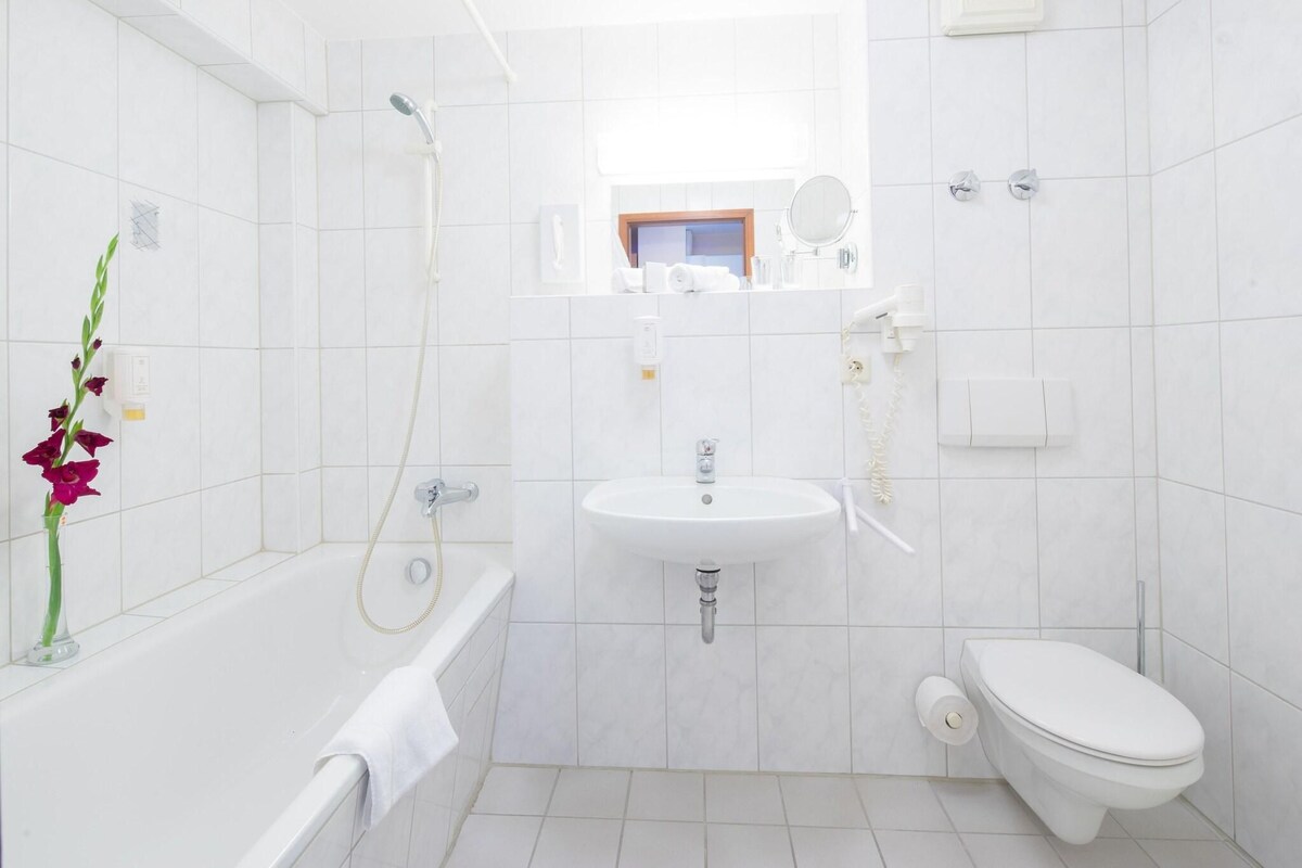 A modern bathroom with a bathtub, sink, toilet, and a shower.