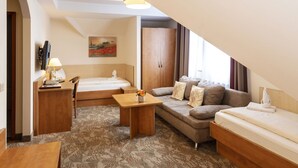 A modern hotel room with a loft bed, a sofa, a small table, and a desk. - Hotel Maximilian (Weil am Rhein)