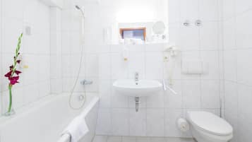 Een moderne badkamer met een bad, wastafel, toilet en douche.