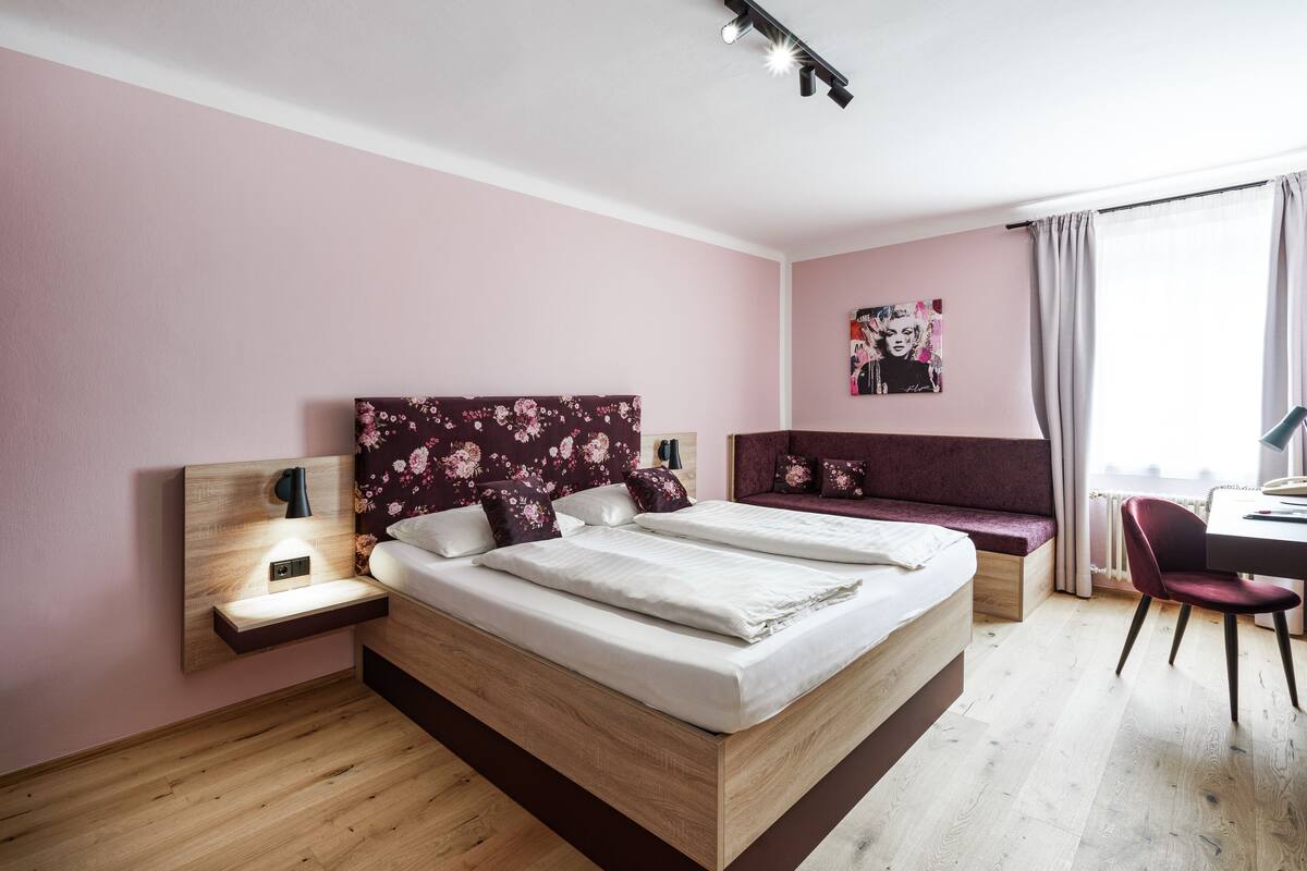 A modern bedroom with a large bed, a desk, and a bench.