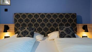 Un letto matrimoniale con testiera decorata, due lampade sui comodini e un quadro appeso alla parete.