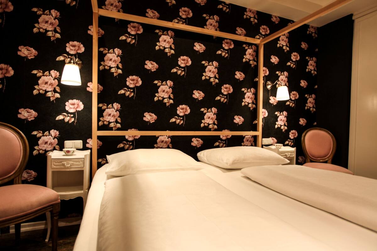 A bedroom with a four-poster bed, two bedside tables, and a chair.