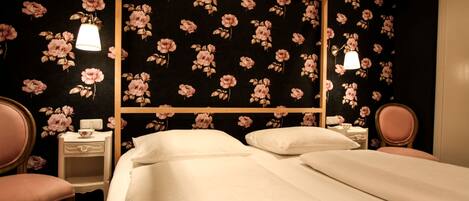 A bedroom with a four-poster bed, two bedside tables, and a chair.