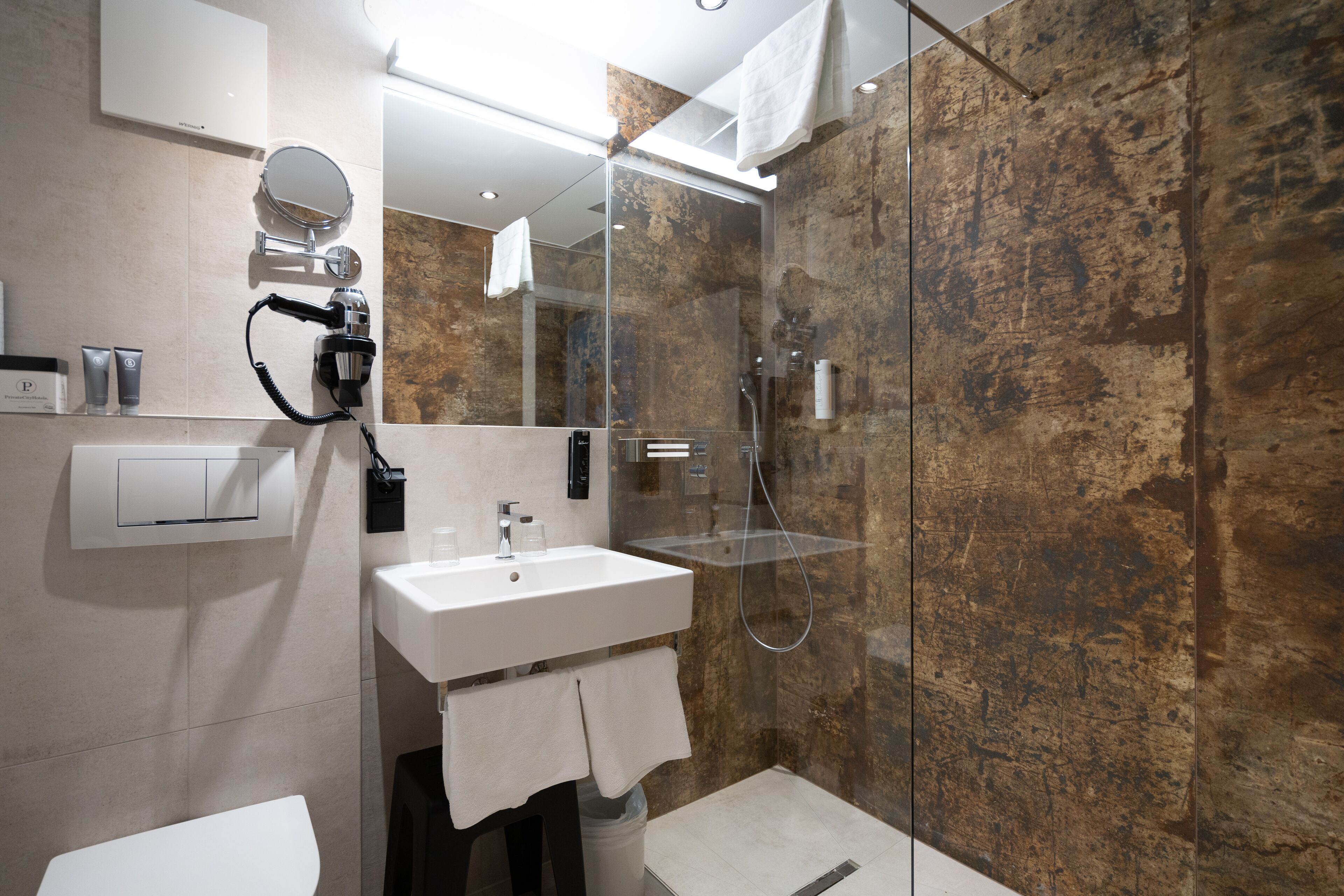 Un baño moderno con cabina de ducha de vidrio, un lavabo blanco y un espejo grande.