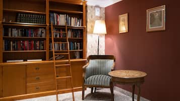 Een bibliotheek met boekenplanken, een stoel, een tafel en een lamp.