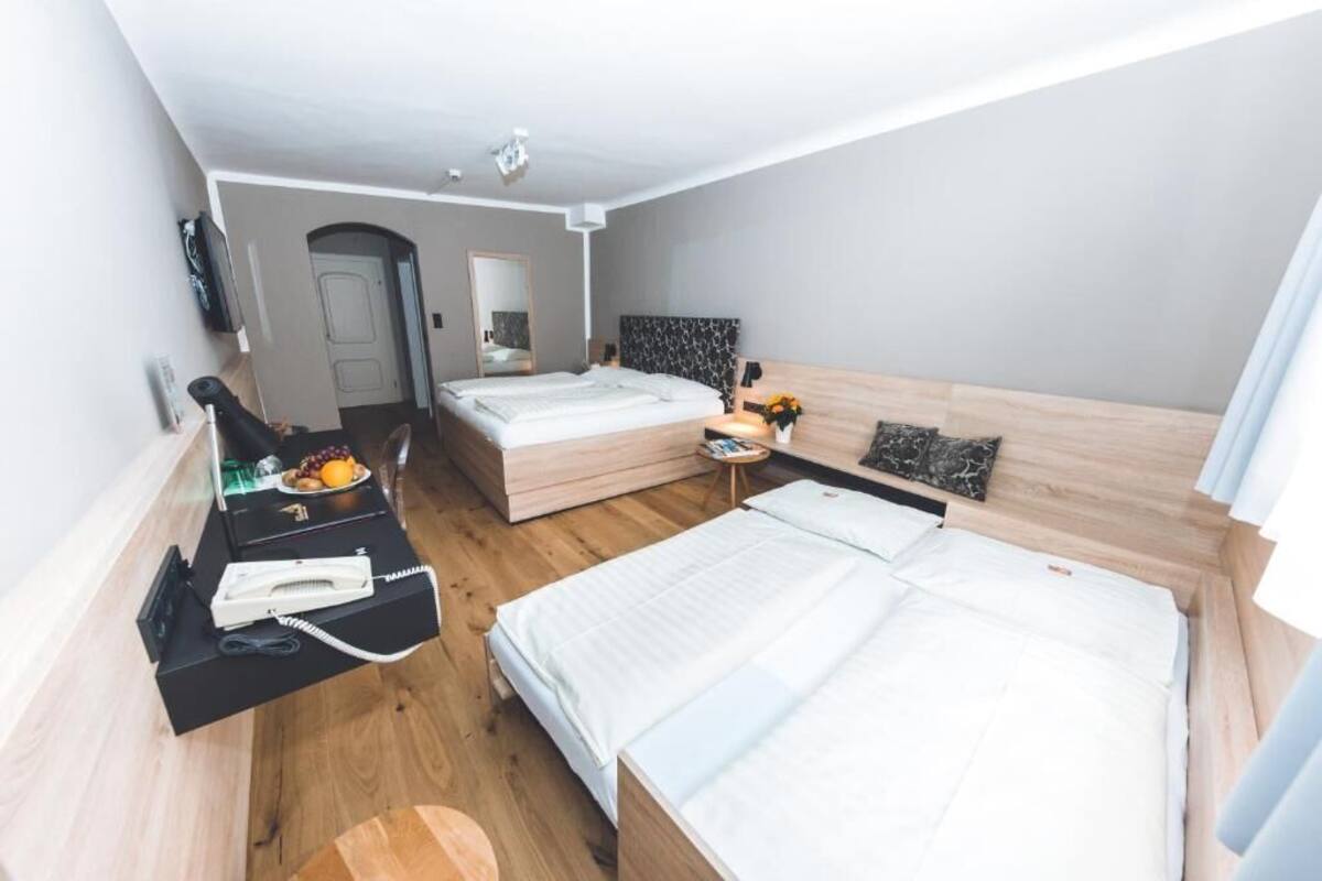 A modern hotel room with a large bed, a desk with a telephone, and a small table with a vase of flowers.