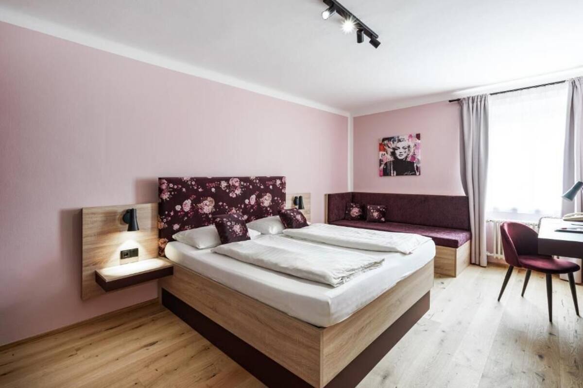 A modern bedroom with a large bed, a desk, and a bench.