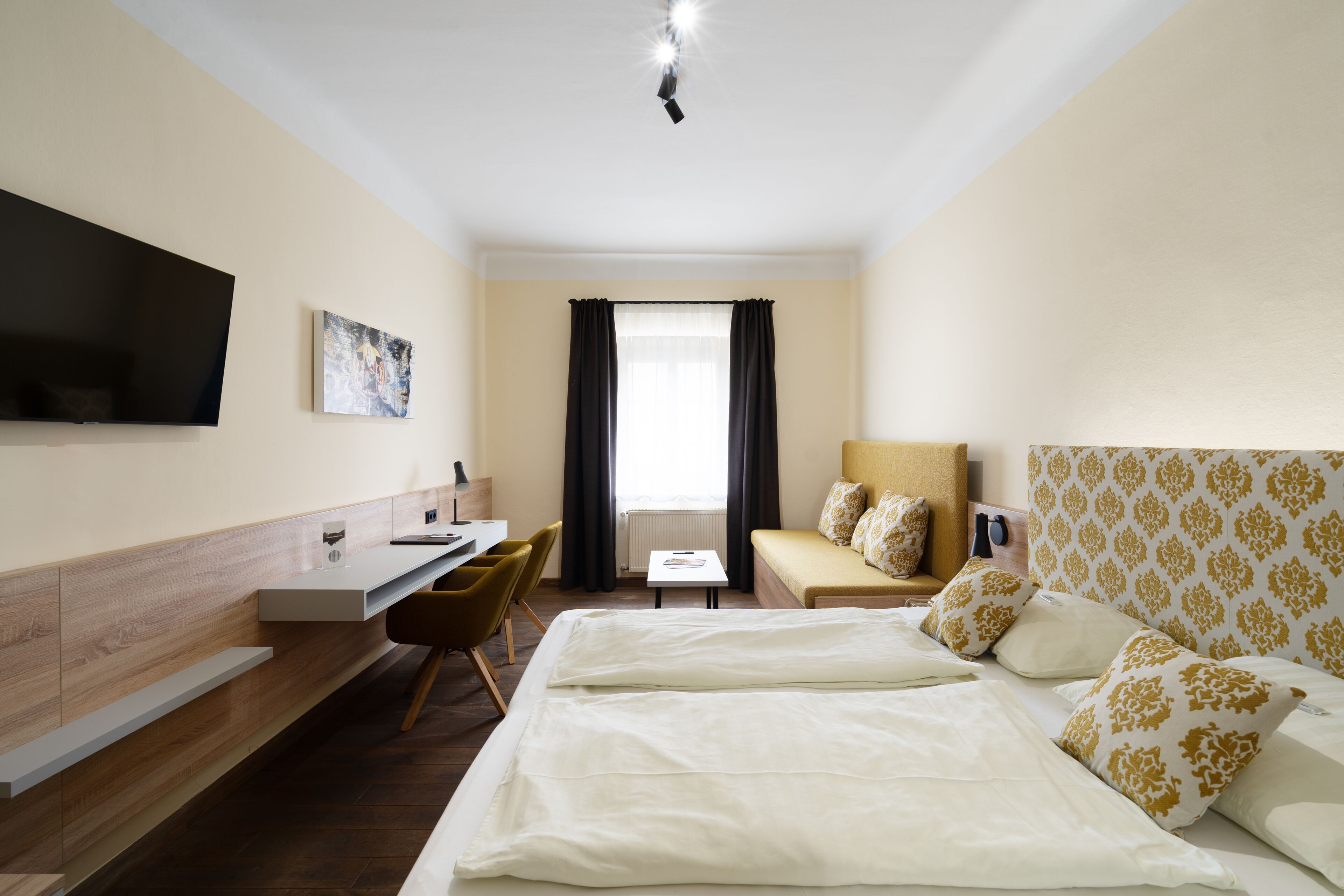 Une chambre d’hôtel équipée d’un lit, d’un bureau, d’une chaise, d’une télévision et d’une fenêtre avec des rideaux.