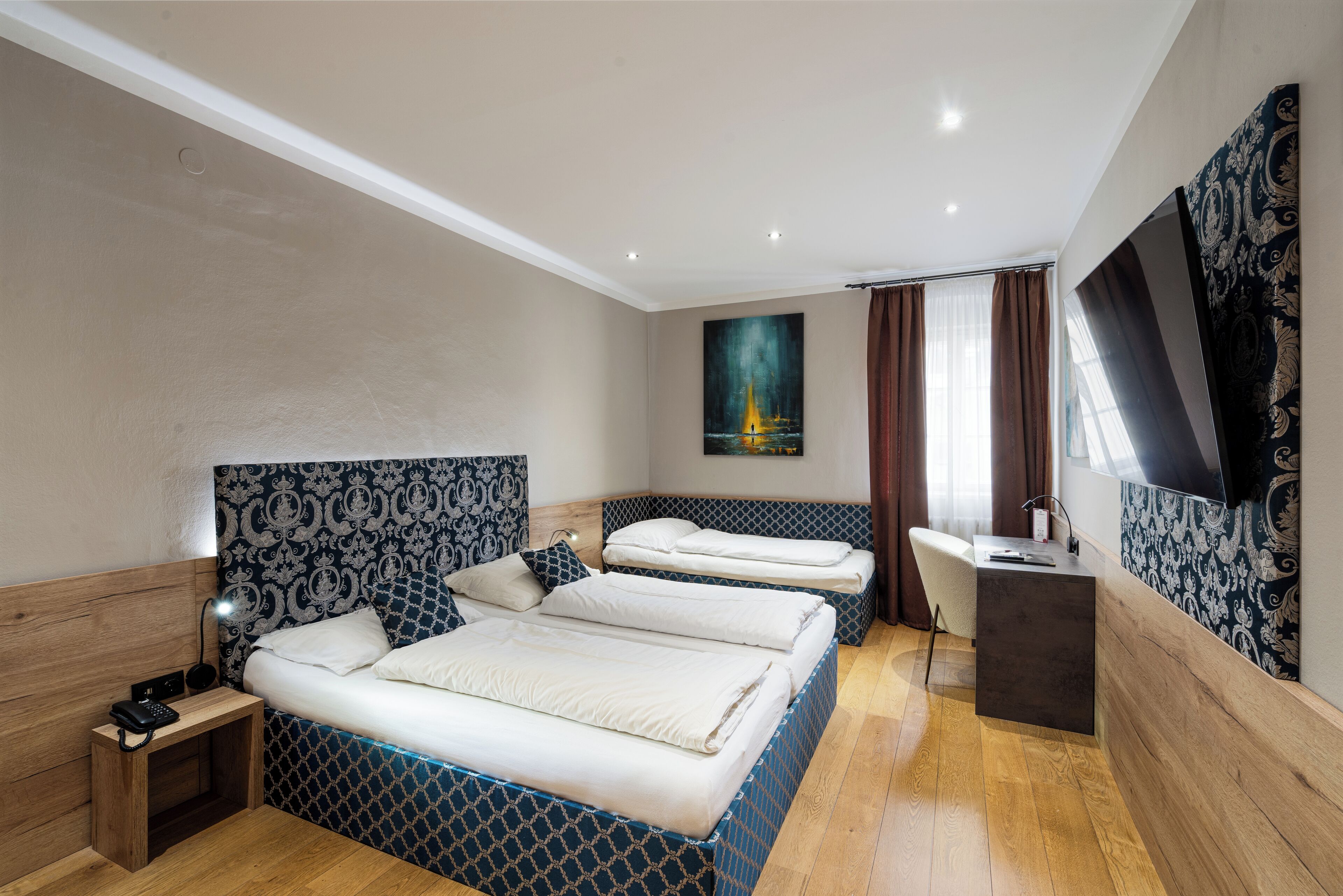 A hotel room with two beds, a desk, a chair, a TV, and a painting on the wall.