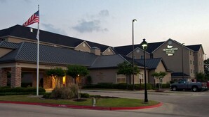 Un hotel de fachada de piedra, una bandera y un letrero que dice Homewood Suites.
