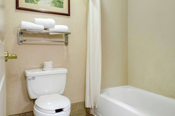 Un baño con inodoro, estante con toallas y bañera.