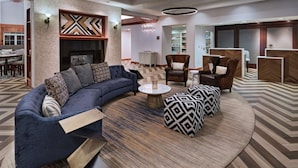 Un moderno vestíbulo de hotel con una zona de estar curva, una chimenea y un candelabro.