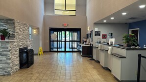 A spacious lobby with a stone wall, a reception desk, and a large window. - Hampton Inn Brattleboro (Brattleboro)
