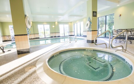 A large indoor swimming pool with clear water, surrounded by tiled walls and a ceiling with recessed lighting.