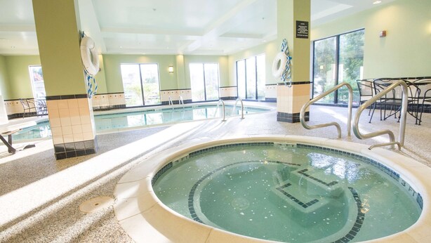 A large indoor swimming pool with clear water, surrounded by tiled walls and a ceiling with recessed lighting. - Hampton Inn Brattleboro (Brattleboro)