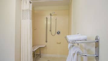 A bathroom with a shower, grab bars, a towel rack, and a small bench.